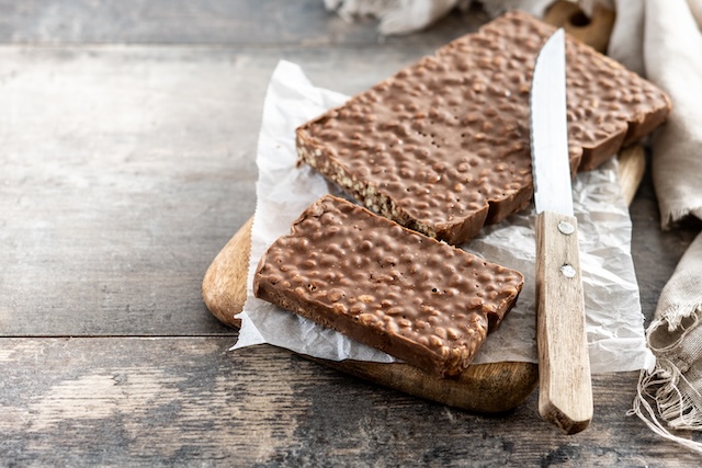 turrón de chocolate con almendras cortado sobre tabla de madera

