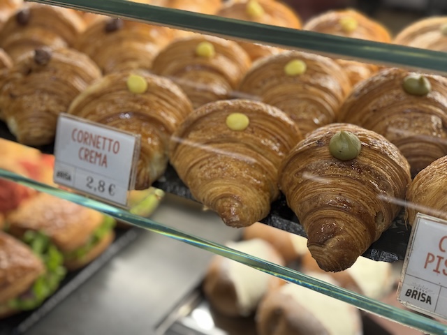 Cornetti clásicos recién horneados en el mostrador de una panadería artesanal italiana