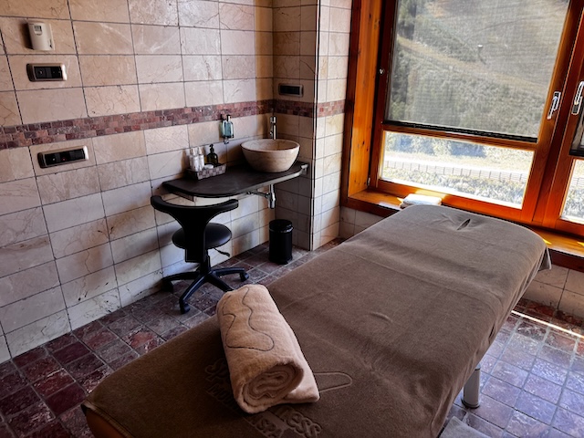 Cabina de masaje con camilla, toalla enrollada y lavabo de piedra en el spa SportWellness, Sport Hotel Hermitage, Soldeu