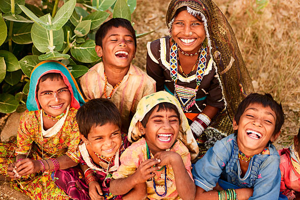 Grupo de niños sonriendo y riendo al aire libre, vestidos con ropa colorida, en la India.