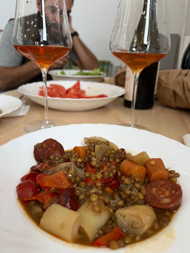 Plato de lentejas con verduras y chorizo junto a dos copas de vino